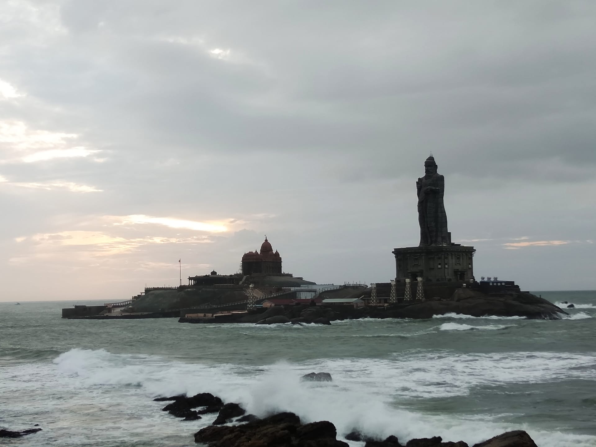 The 41-metre Thiruvalluvar Statue and the Vivekananda Rock Memorial at Kanyakumari, Tamil Nadu, at dusk, with waves breaking around the island.